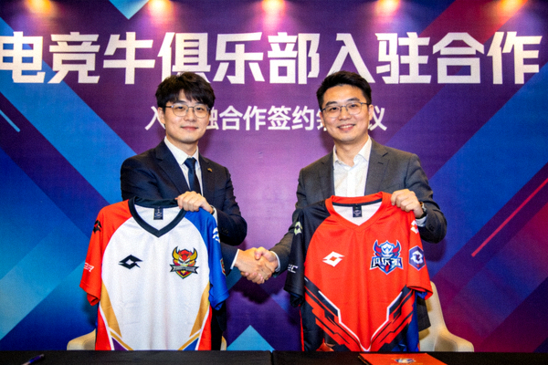 电竞牛俱乐部入驻合作签约仪式上，双方代表在背景板前握手并展示联名队服