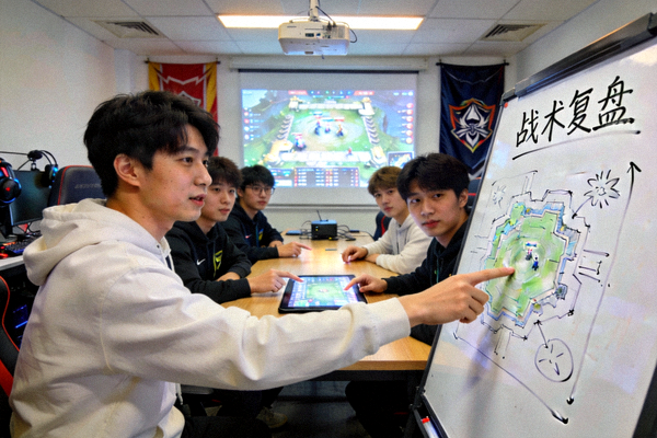 电竞牛青训营年轻选手们围坐在训练室里，通过白板与比赛录像进行战术复盘